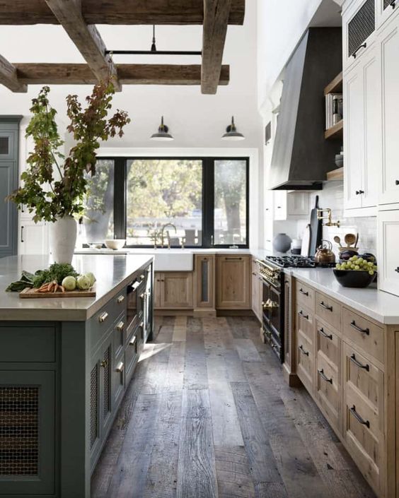 An inviting modern farmhouse kitchen with stained and white cabinets, a gray island and hood, and exposed beams