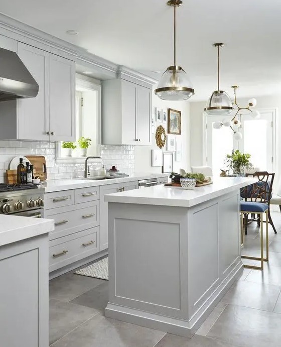 an airy dove gray kitchen with shaker cabinets, a white subway tile backsplash, white countertops and chic pendant lamps