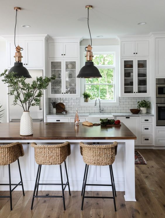 a white modern farmhouse kitchen with shaker cabinets, a white subway tile backsplash, an island and wicker stools