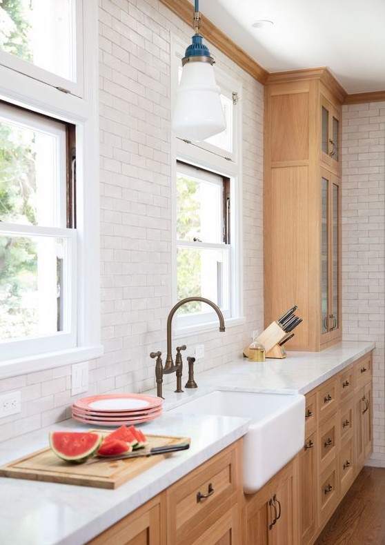 a sleek kitchen with light-stained Shaker-style cabinets, a white subway tile backsplash, and white stone countertops