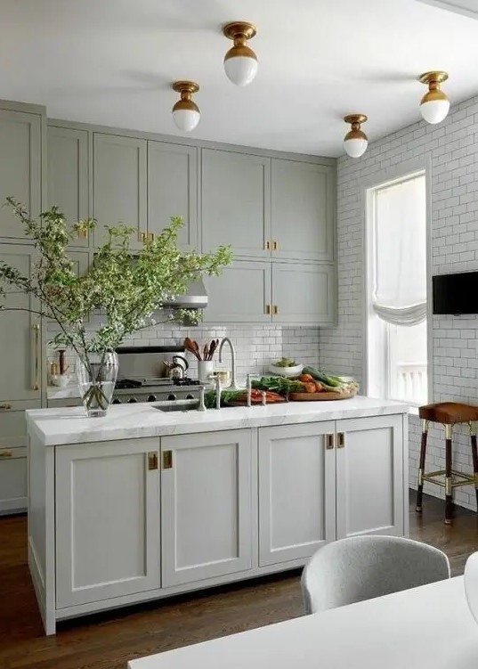 An amazing lime green modern farmhouse kitchen with shaker cabinets, white subway tiles and brass accents for added elegance