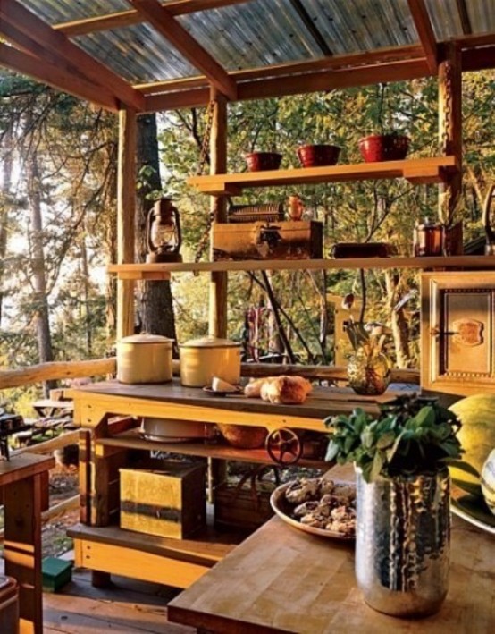 a small outdoor kitchen with wooden cabinets and open shelving to enjoy the views, yellow accents and candle lanterns