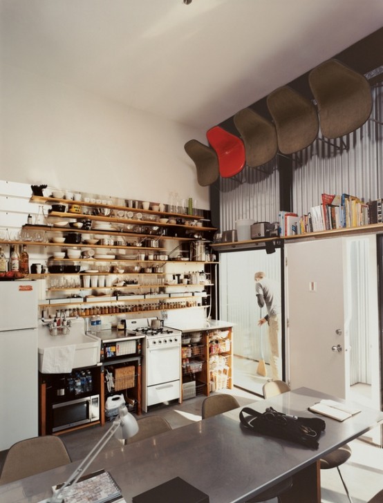 a small but functional kitchen with open cabinets, an oversized shelf that takes up the entire wall and some appliances
