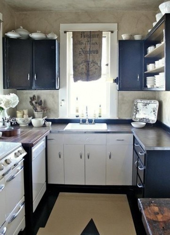 A small vintage navy and white kitchen with dark stained countertops and a geometric rug