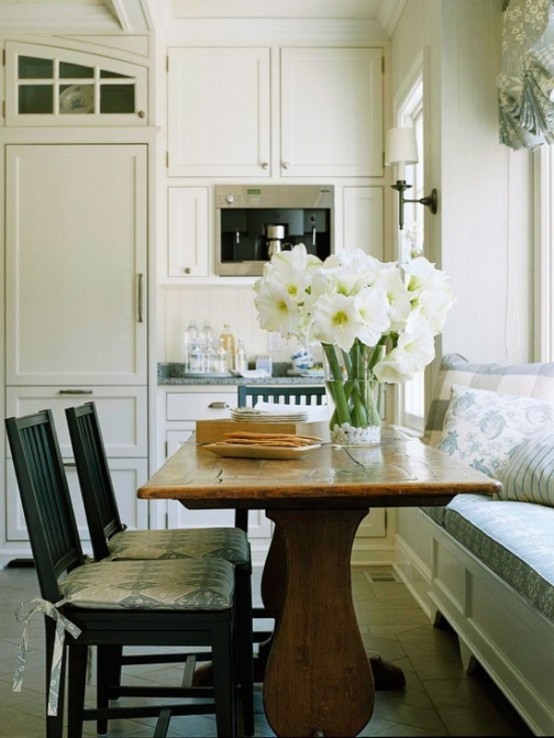 a small neutral farmhouse kitchen with gray countertops, a wooden table, black chairs and an upholstered blue bench