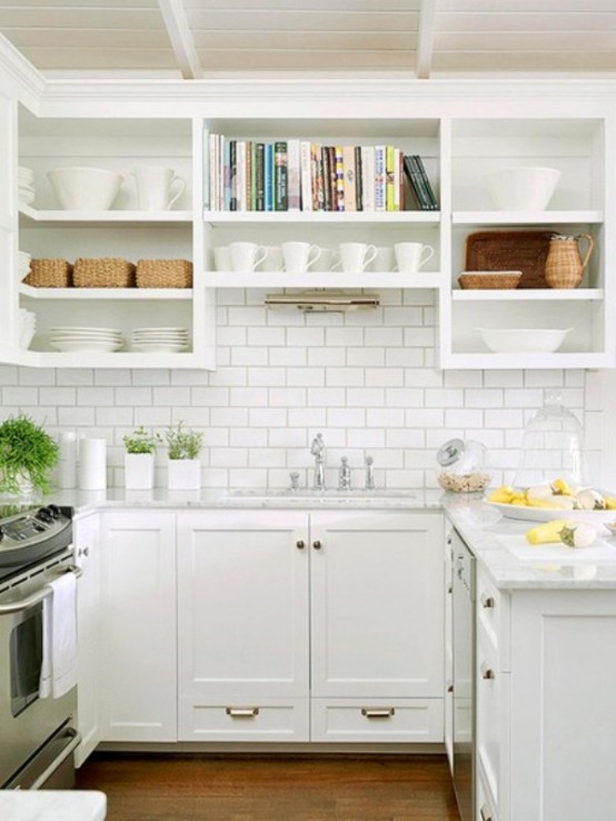 A small but stylish farmhouse kitchen in white with gold hardware, white subway tiles and open shelves and drawers for storage