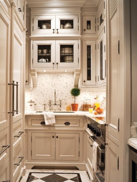 a small, cream-colored, vintage-style kitchen with plenty of storage space, a tiled splashback and additional lights for comfortable cooking