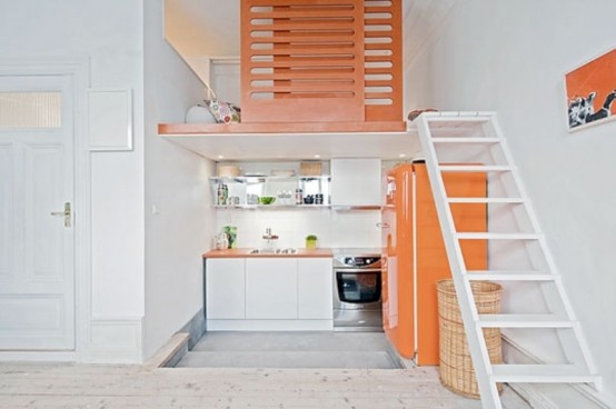 a bright small kitchen with white cabinets, a bright orange refrigerator, orange countertops and lime accents