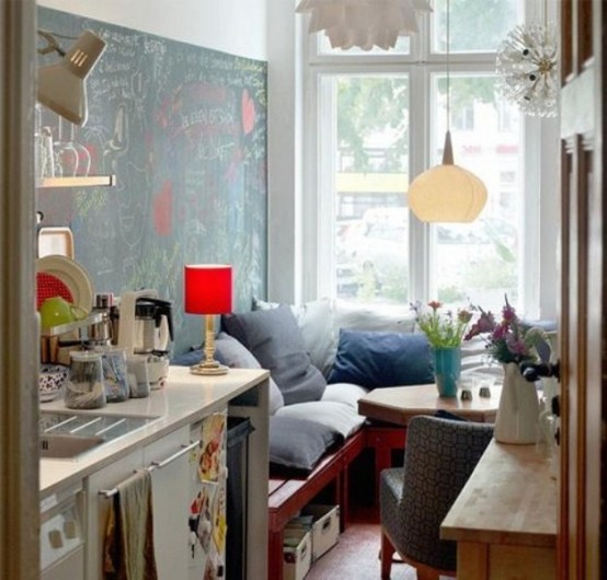 a small, versatile kitchen with a few cupboards and a cozy corner by the window with a hexagonal table