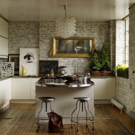 a small, glamorous kitchen with brick walls, white cabinets and metal countertops, as well as a frosted glass chandelier