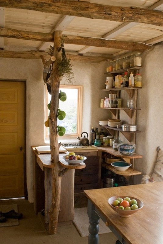 a small rustic kitchen with open shelves, a worktop, wooden beams and wooden furniture