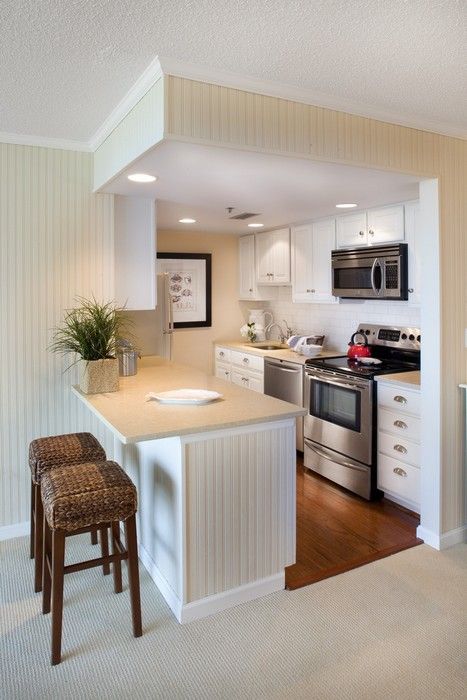 a small traditional off-white kitchen arranged in a cube with a kitchen island separating the rooms