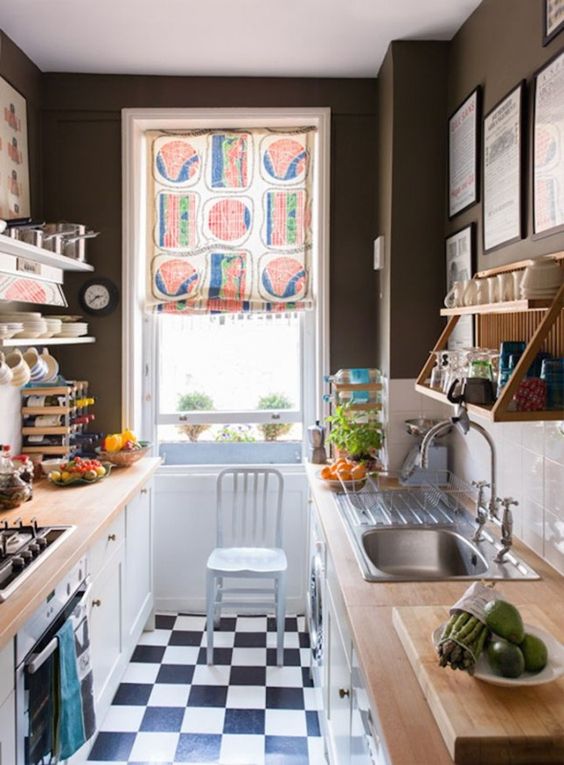a small, monochromatic kitchen with black walls, a white subway tile backsplash, butcher block countertops and a colorful screen