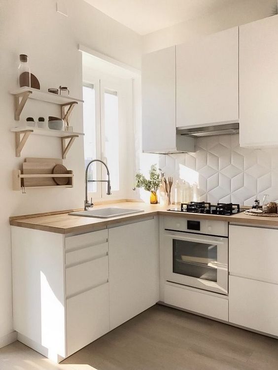 a small, minimalist kitchen with sleek white cabinets, light-stained wood countertops, a white tile backsplash, and open shelving