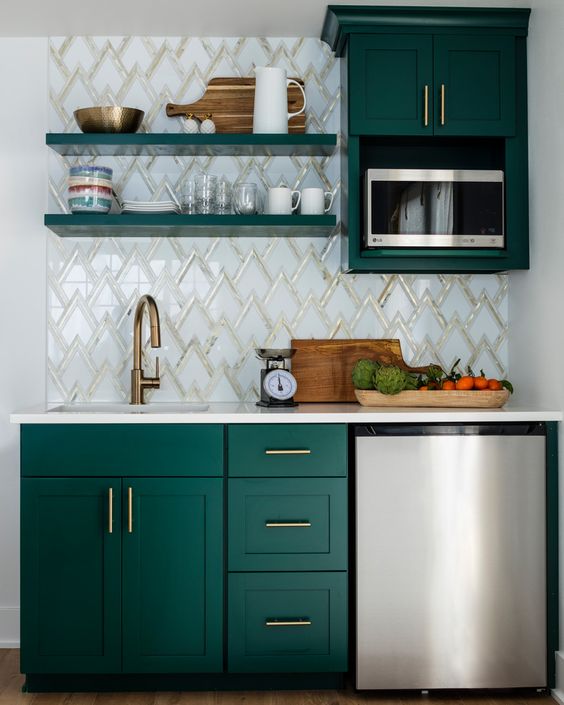 a small kitchen with emerald green cabinets, a mosaic tile backsplash, brass hardware, open shelving and metal appliances