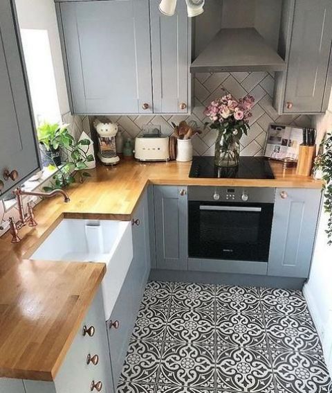 A small gray farmhouse kitchen with mosaic tile flooring, butcher block countertops and a white chevron tile backsplash