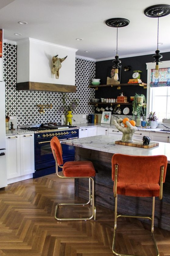 a bold, eclectic kitchen with white cabinets, a navy stove, island, rust-colored stools, and an over-the-range hood