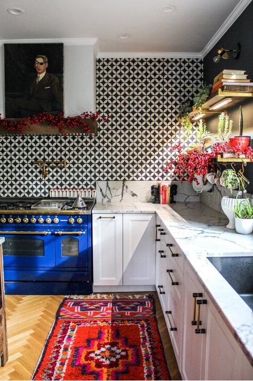 a striking, eclectic kitchen with white shaker-style cabinets, a statement blue stove, a bright rug, a black-and-white tile backsplash, and a portrait