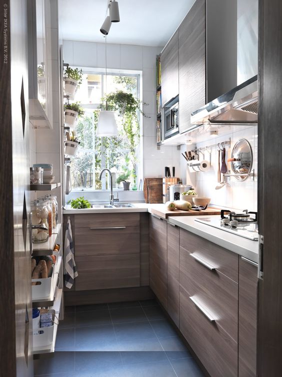 a modern small kitchen with sleek cabinets, simple hardware, a window and a black tile floor