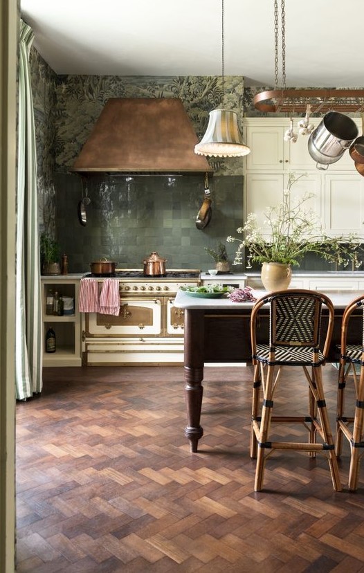 a chic, atmospheric, eclectic kitchen with white cabinets, a vintage stove, a copper hood, pendant lamps and a large vintage-style kitchen island