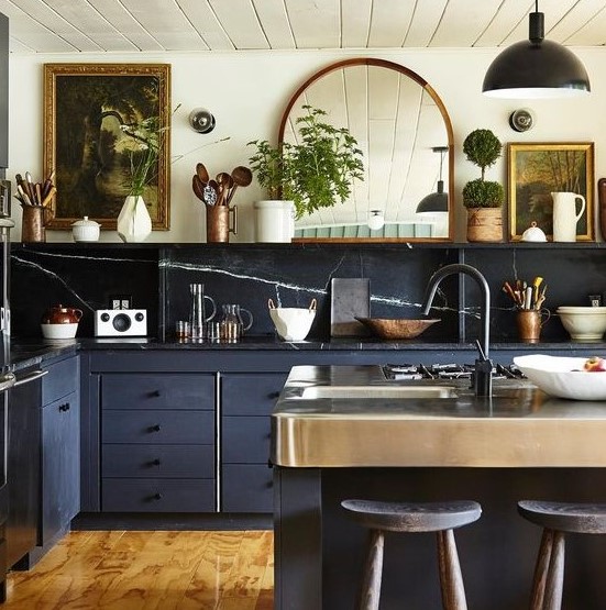 A beautiful, eclectic kitchen combining stone splashbacks and countertops, navy blue cabinets, vintage artwork and a mirror