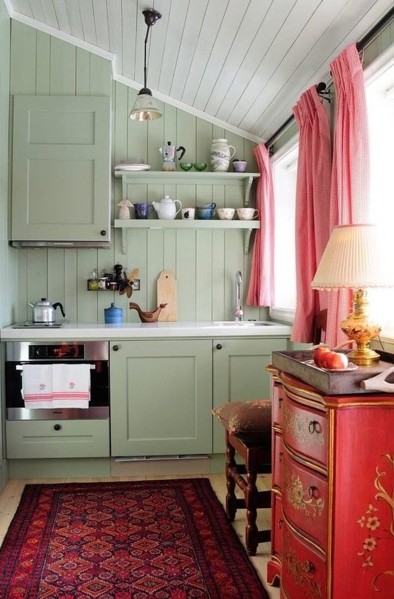 a beautiful maximalist kitchen with olive green walls and a kitchen, a red chest of drawers, a sophisticated stool, pink curtains and a light carpet
