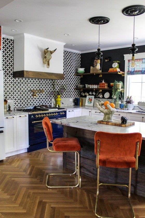 a stylish maximalist kitchen with black walls and accent tiles, white cabinets and a navy stove, rusty chairs and a marble countertop