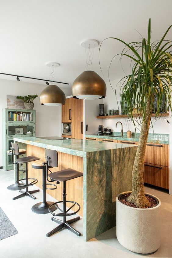 an eclectic kitchen with fluted cabinets and green marble countertops, a green shabby chic storage cabinet, pendant lamps and brass stools