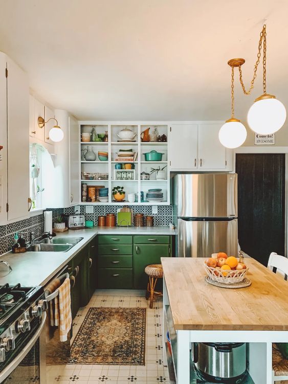 an eclectic kitchen with green and white cabinets, a printed tile backsplash and white countertops, a farmhouse-style kitchen island