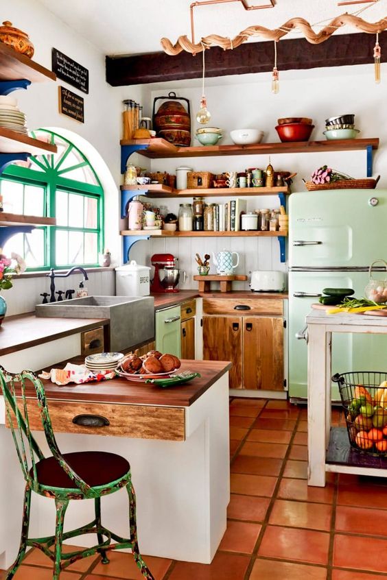 an eclectic kitchen with white and stained cabinets, a lime green refrigerator, open shelving and pendant lamps, and some shabby-chic furniture