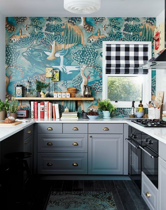 A particularly eye-catching, eclectic kitchen features gray shaker cabinets, bold printed wallpaper, open shelving, greenery and a checkered curtain