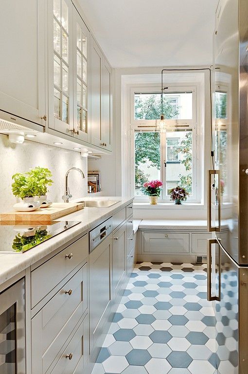 a beautiful white kitchen with white countertops, a white backsplash, a hexagonal tile floor and a windowsill