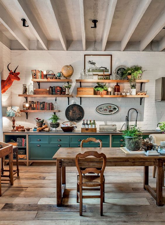 A bright, eclectic kitchen with teal cabinets, rustic wood cabinetry, potted plants, and a faux animal head