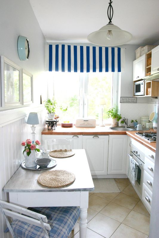 a cozy coastal kitchen with white cabinets, statement countertops, striped and checked textiles, and pendant lamps