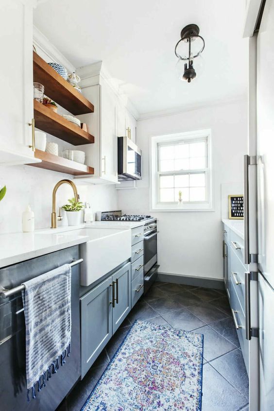 A gray and white kitchen with open shelving, gold accents, and printed rugs is a cool space