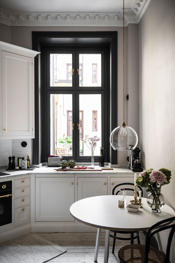 a beautiful French-style kitchen in black and white, with sophisticated chairs, a round table and gilded accents