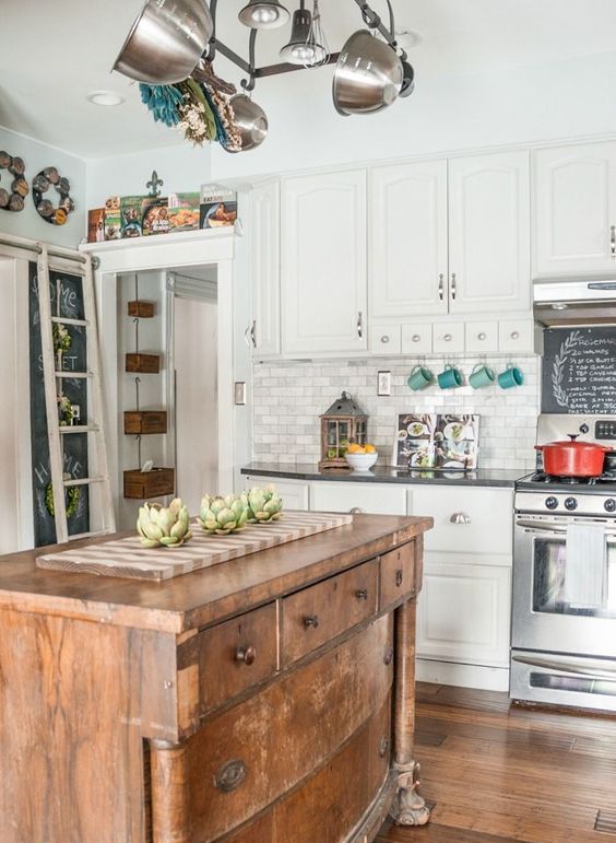 A white, traditional kitchen with dark countertops, spiced up with a vintage wooden kitchen island to make it more relaxed
