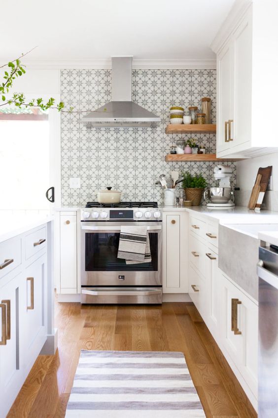 A pretty neutral kitchen with a printed tile backsplash, brass handles, potted plants and woven planters