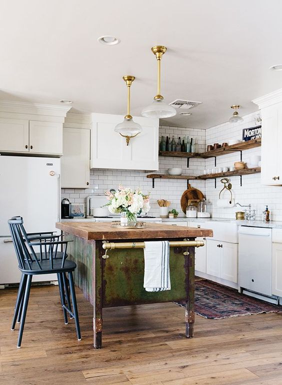 White cabinets paired with a shabby chic wooden kitchen island and vintage blue stools and sophisticated pendant lamps