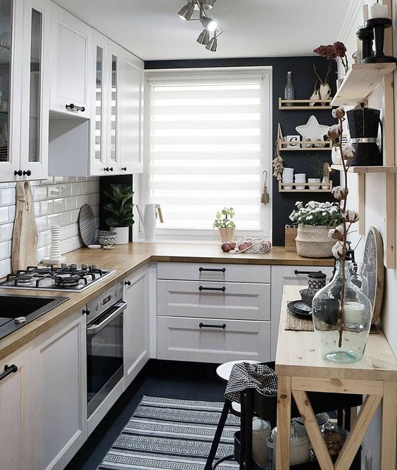 a small Scandinavian kitchen with a white tile backsplash, butcher block countertops, open shelving and black walls