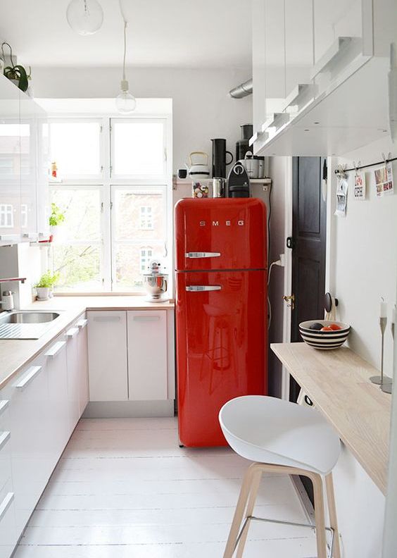 a small white Scandinavian-style kitchen, light wood countertops and a bold red fridge for a touch of color