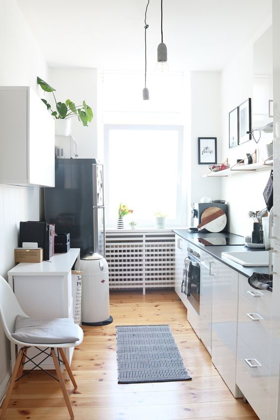 a stylish Scandinavian kitchen with black countertops, a black refrigerator, open shelving and a mini kitchen island