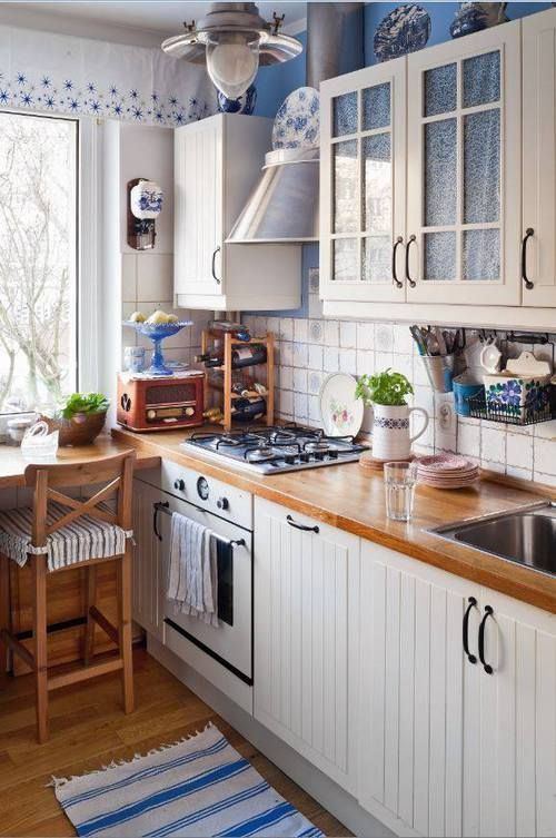 a white farmhouse kitchen with butcher block countertops, high stools and blue accents for comfort