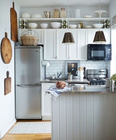 a white farmhouse kitchen with subway tiles, a kitchen island and pendant lamps, and wood elements