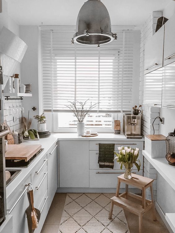 a white Scandinavian kitchen with white worktops, pendant lamps and wooden elements here and there