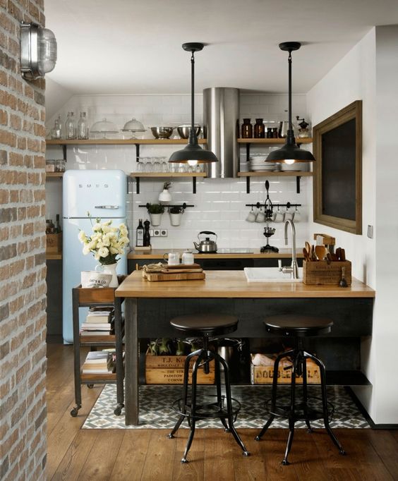 an industrial kitchen with black cabinets, butcher block countertops, a white tile backsplash, and pendant lights