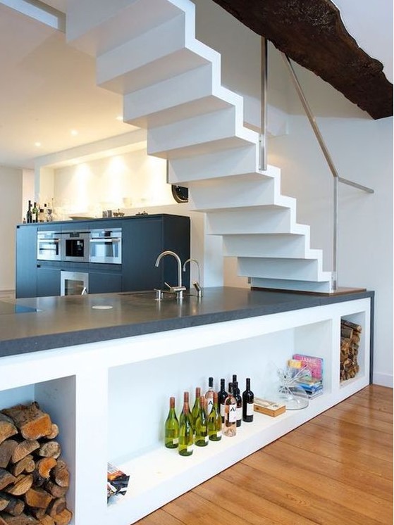 a black modern kitchen with an island under the stairs, with storage compartments and lights