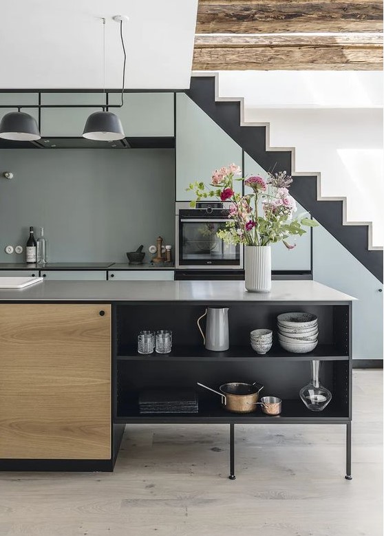 a cool, modern kitchen with a staircase and built-in light blue cabinets, a black and stained kitchen island
