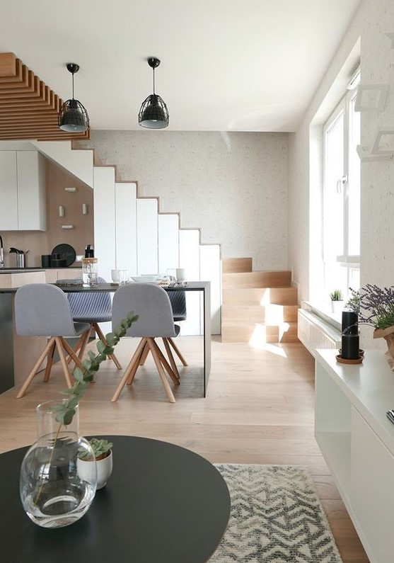 a modern space with a staircase that includes storage and stained and white cabinets, black countertops and decor