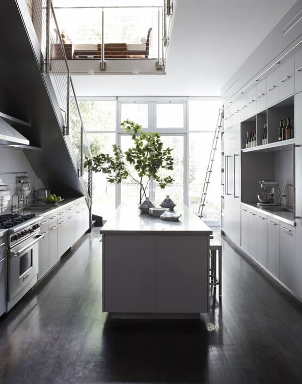 a Scandinavian kitchen with white cabinets, part of which is under the stairs, with a large kitchen island and lots of natural light